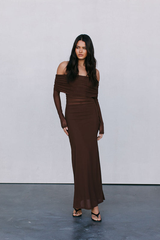 Woman wearing a brown off-shoulder dress against a plain background