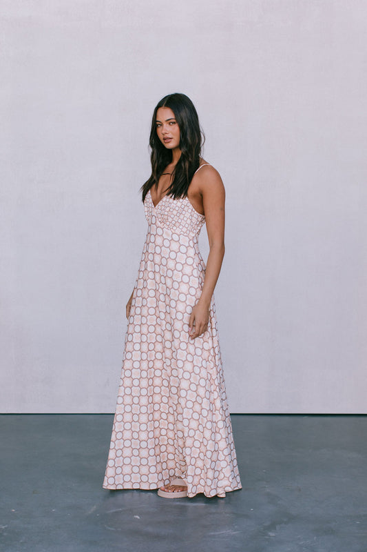Woman in a patterned dress standing against a plain background