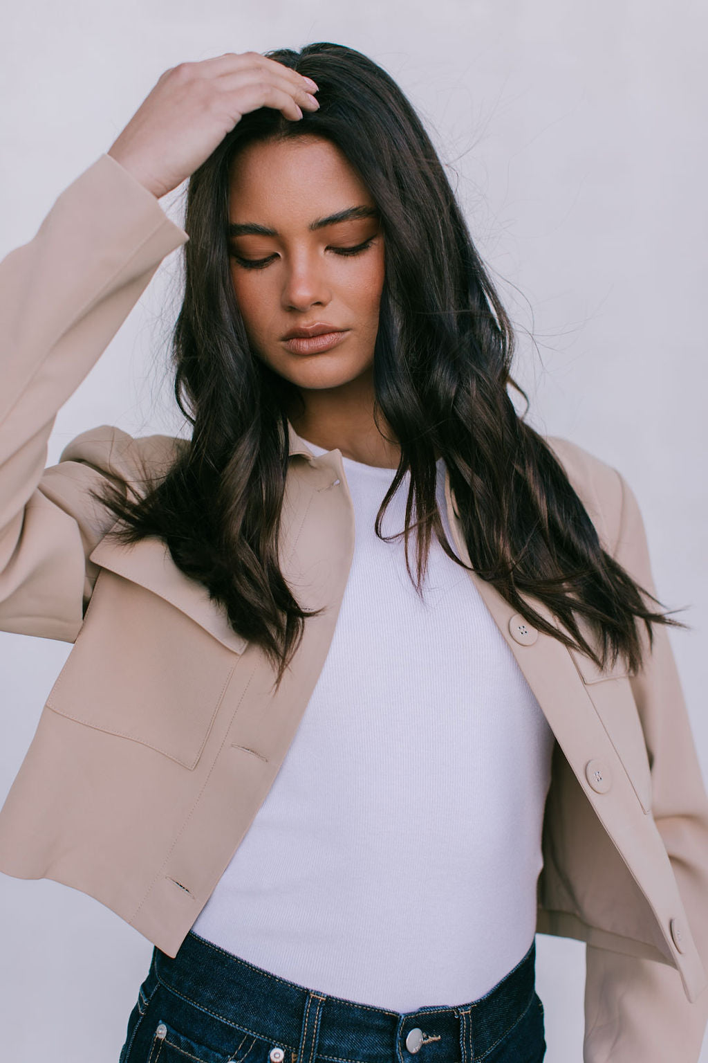 Woman wearing a beige blazer over a white top with a plain background
