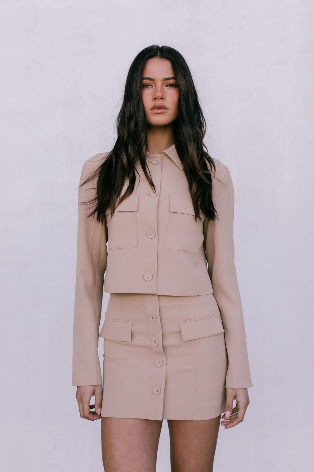 Woman wearing a beige outfit against a plain background