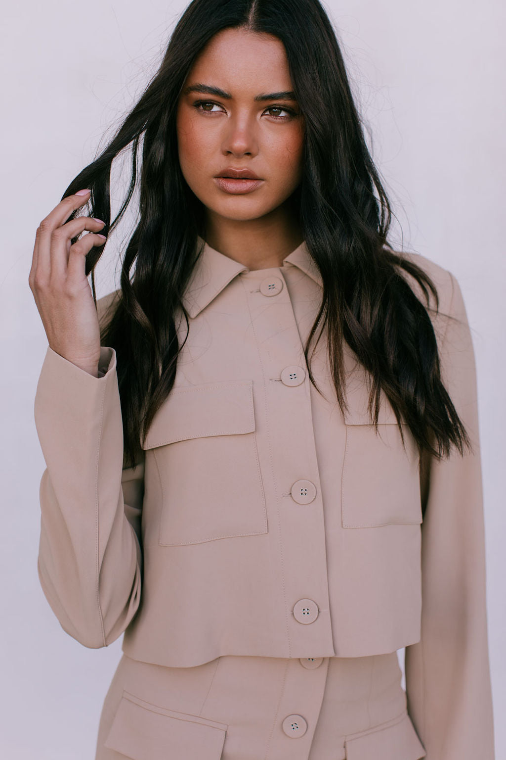 Woman wearing a beige suit against a white background