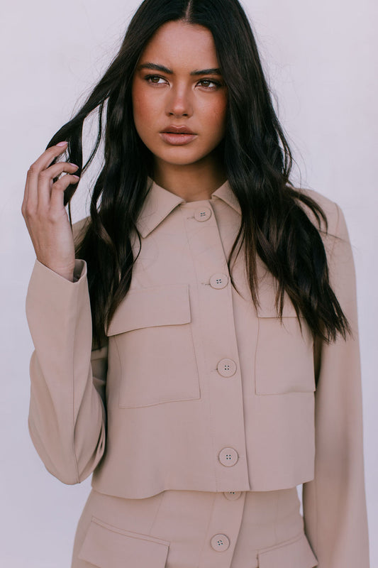 Woman wearing a beige suit against a white background