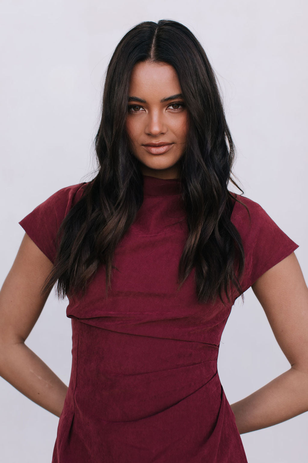 Woman wearing a burgundy dress against a plain background