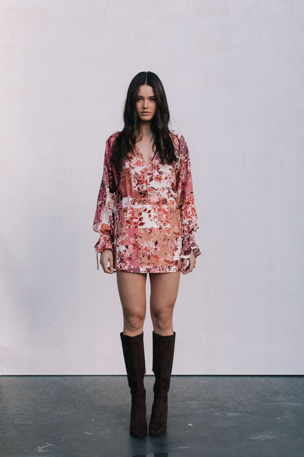 Woman wearing a floral dress and brown boots against a white background