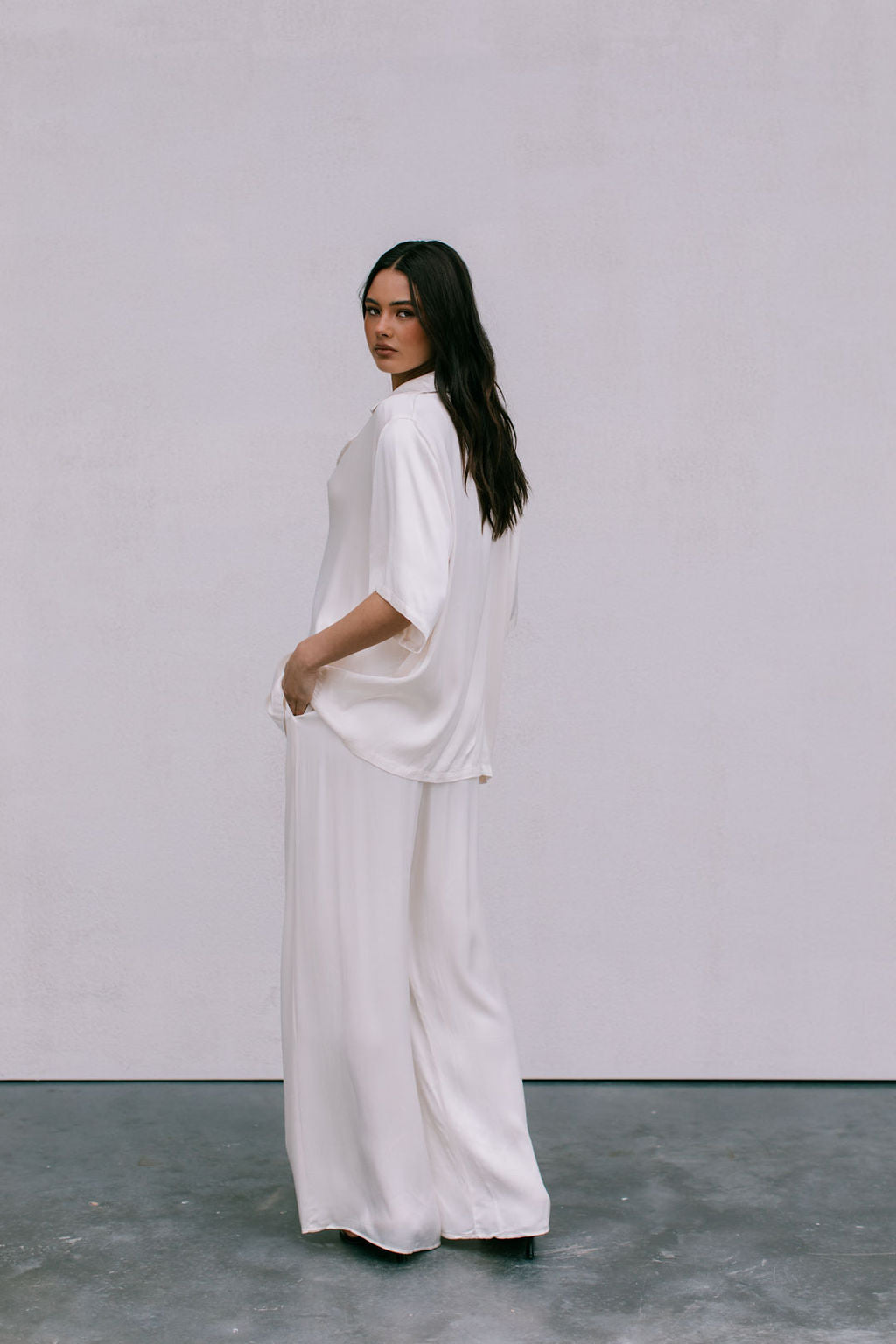Woman wearing a white outfit standing against a plain background