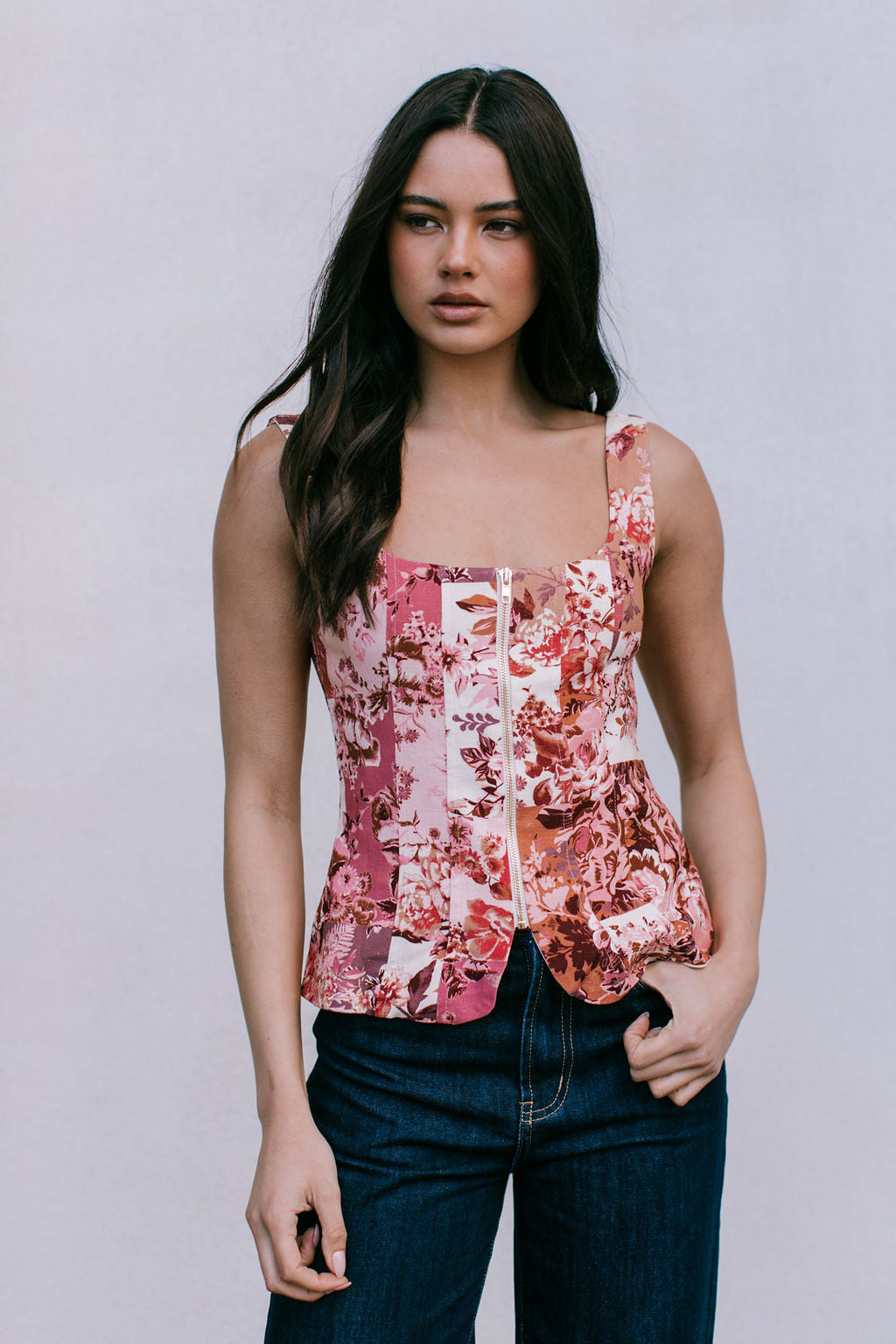 Woman wearing a floral sleeveless top against a plain background