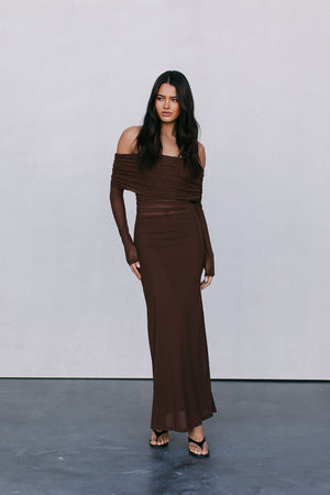 Woman wearing a brown off-shoulder dress against a plain background