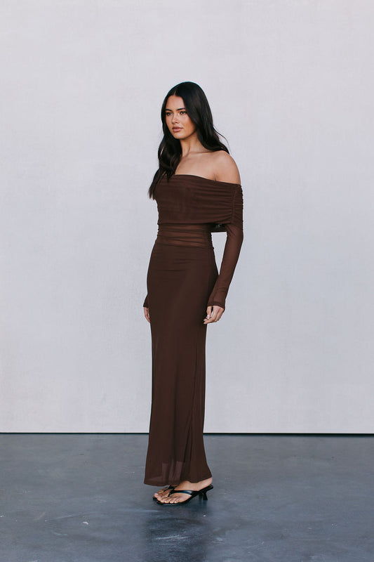 Woman wearing a brown off-shoulder dress against a plain background