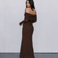 Woman wearing a brown off-shoulder dress against a plain background