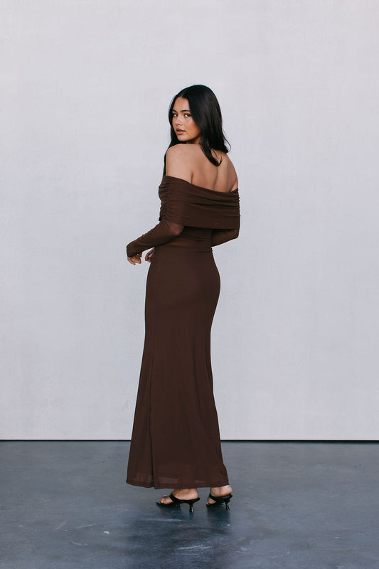 Woman wearing a brown off-shoulder dress against a plain background