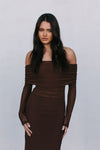 Woman wearing a brown off-shoulder dress against a plain background