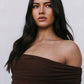 Woman wearing a brown off-shoulder top against a plain background