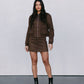 Woman wearing a brown jacket and skirt set with black boots against a plain background