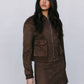 Woman wearing a brown suede jacket and skirt on a plain background