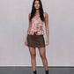 Woman wearing a floral top and brown skirt against a plain background