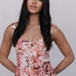 Woman wearing a floral sleeveless top against a plain background
