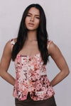 Woman wearing a floral sleeveless top against a plain background