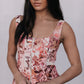 Woman wearing a floral sleeveless top against a plain background