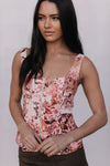 Woman wearing a floral sleeveless top against a plain background