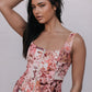 Woman wearing a floral sleeveless top against a plain background