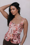 Woman wearing a floral sleeveless top against a plain background