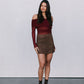 Woman wearing a burgundy off-shoulder top and brown skirt against a white background