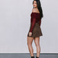 Woman wearing a burgundy off-shoulder top and brown skirt with black boots against a white background