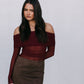 Woman wearing a burgundy off-shoulder top and brown skirt against a white background