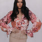 Woman wearing a floral blouse and beige skirt against a plain background