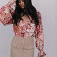 Woman wearing a floral blouse and beige skirt against a white background