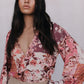 Woman wearing a floral blouse with long sleeves against a plain background