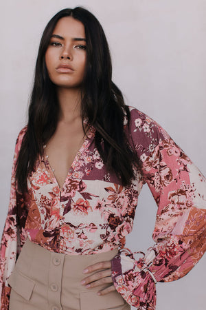 Woman wearing a floral blouse with long sleeves against a plain background