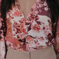 Person wearing a floral blouse with a deep neckline and beige pants.
