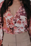 Person wearing a floral blouse with a deep neckline and beige pants.