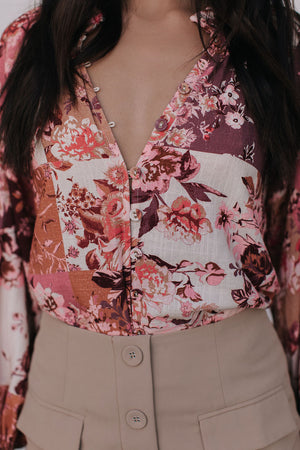 Person wearing a floral blouse with a deep neckline and beige pants.