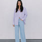 Woman wearing a light purple shirt and light blue jeans against a white background