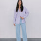 Woman wearing a light purple shirt and light blue jeans against a white background