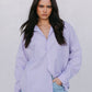 Woman wearing a light purple shirt and light blue jeans against a plain background