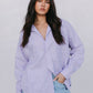 Woman wearing a light purple shirt and light blue jeans against a plain background