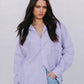 Woman wearing a light purple shirt and light blue jeans against a plain background