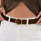 Person wearing a brown belt with a gold buckle on white pants
