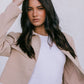 Woman wearing a beige blazer over a white top with a plain background