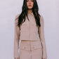 Woman wearing a beige outfit against a plain background
