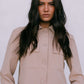 Woman wearing a beige suit against a plain background