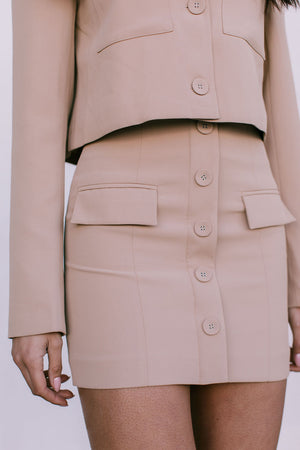 Beige suit jacket and skirt worn by a person on a plain background
