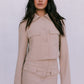 Woman wearing a beige two-piece suit against a white background