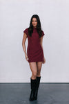 Woman wearing a burgundy dress and black boots against a white background