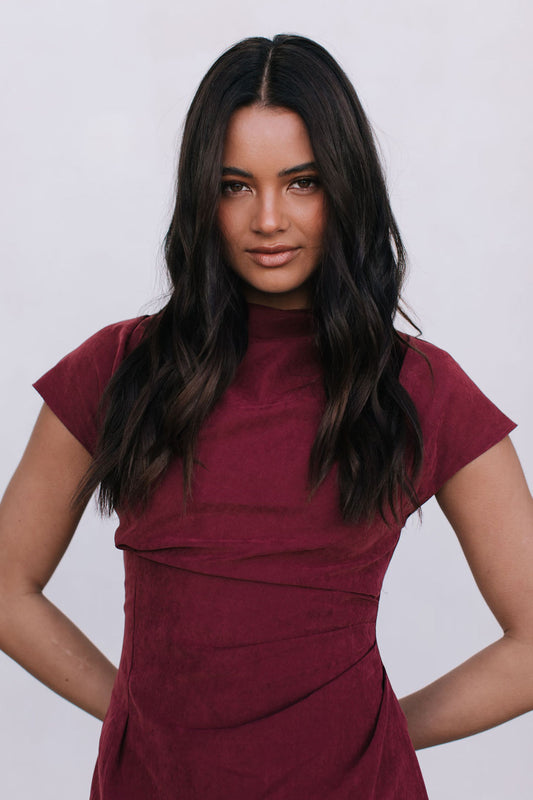 Woman wearing a burgundy dress against a plain background