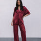 Woman wearing a burgundy satin outfit with lace pants on a plain background