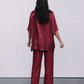 Person wearing a red burgundy satin outfit with a plain white background
